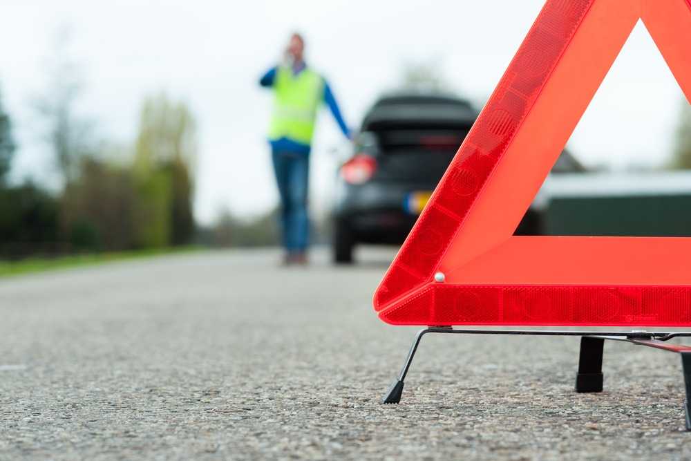 close-up on a roadside sign while a driver calls for help