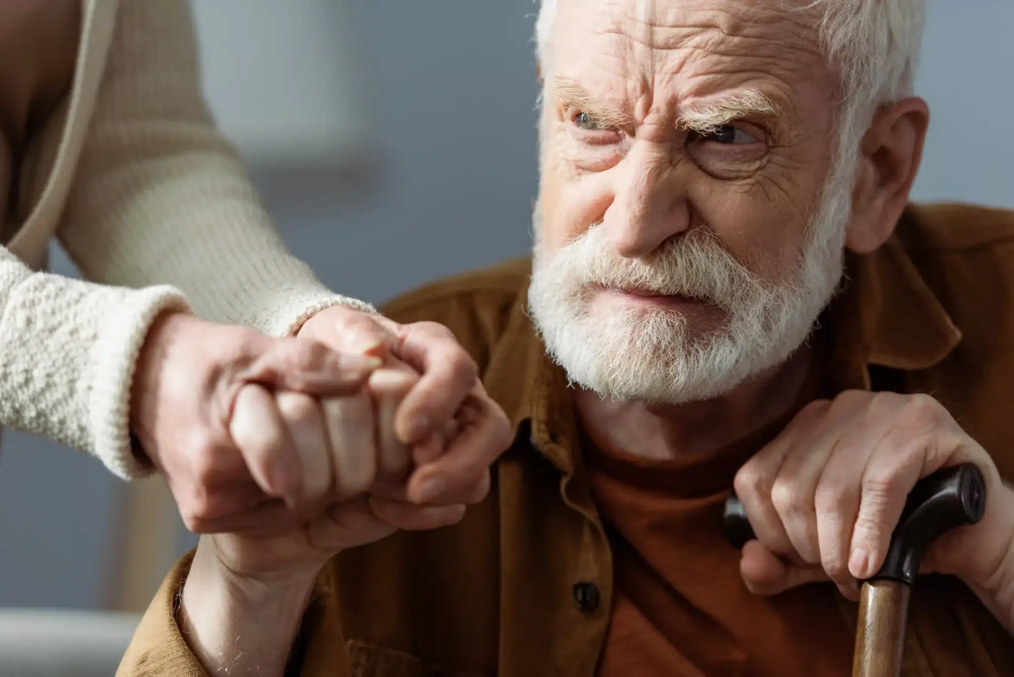 Partial view of a woman holding the hand of an elderly man