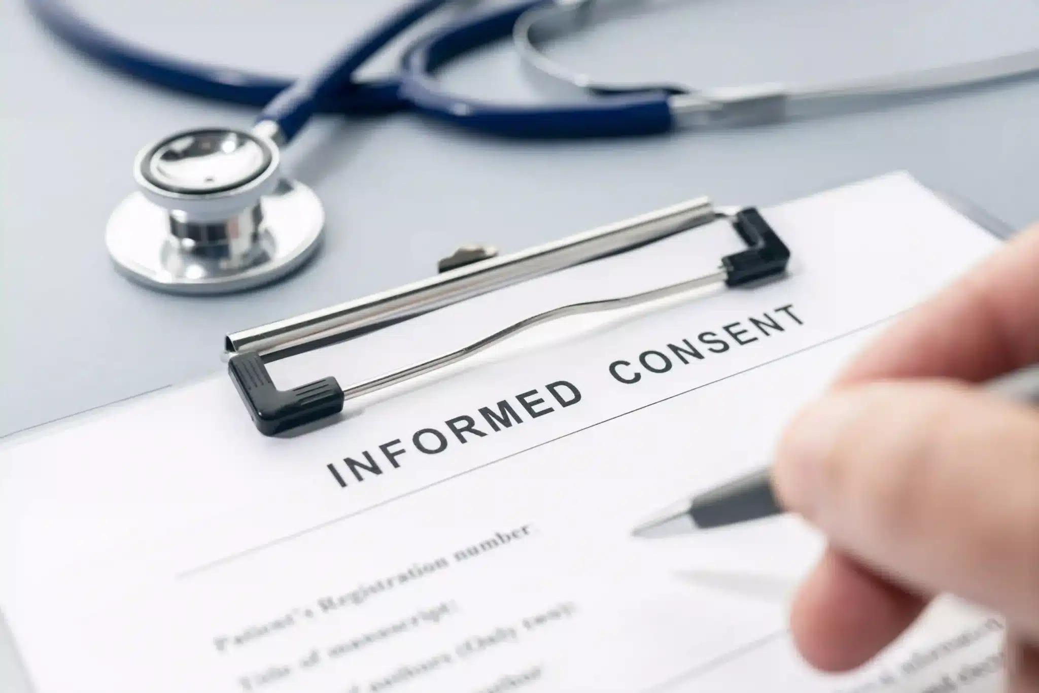 Hand of a man filling out informed consent form on a desk